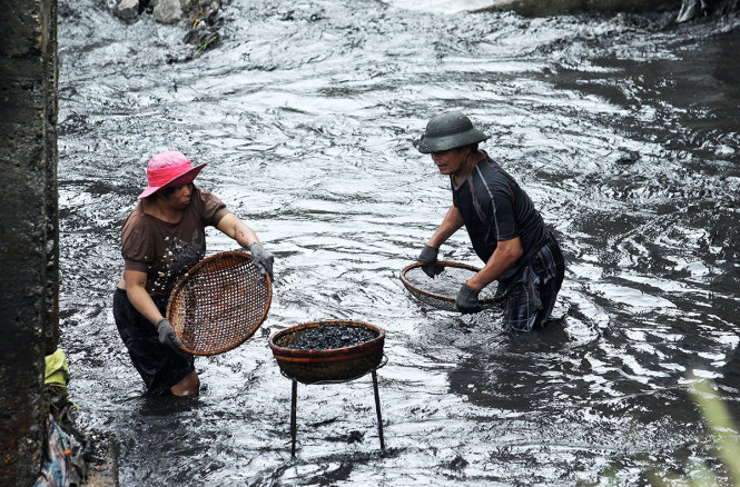 Hai cha con ông Nguyễn Văn Nhợt và chị Nguyễn Thị Liên đang cố gắng nhặt nhạnh than trôi nổi trên dòng suối B5-12 - Ảnh: Nguyễn Khánh