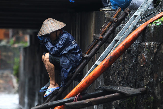 Một người dân tỏ vẻ mệt mỏi sau nửa ngày làm việc nặng nhọc dưới nước - Ảnh: Nguyễn Khánh